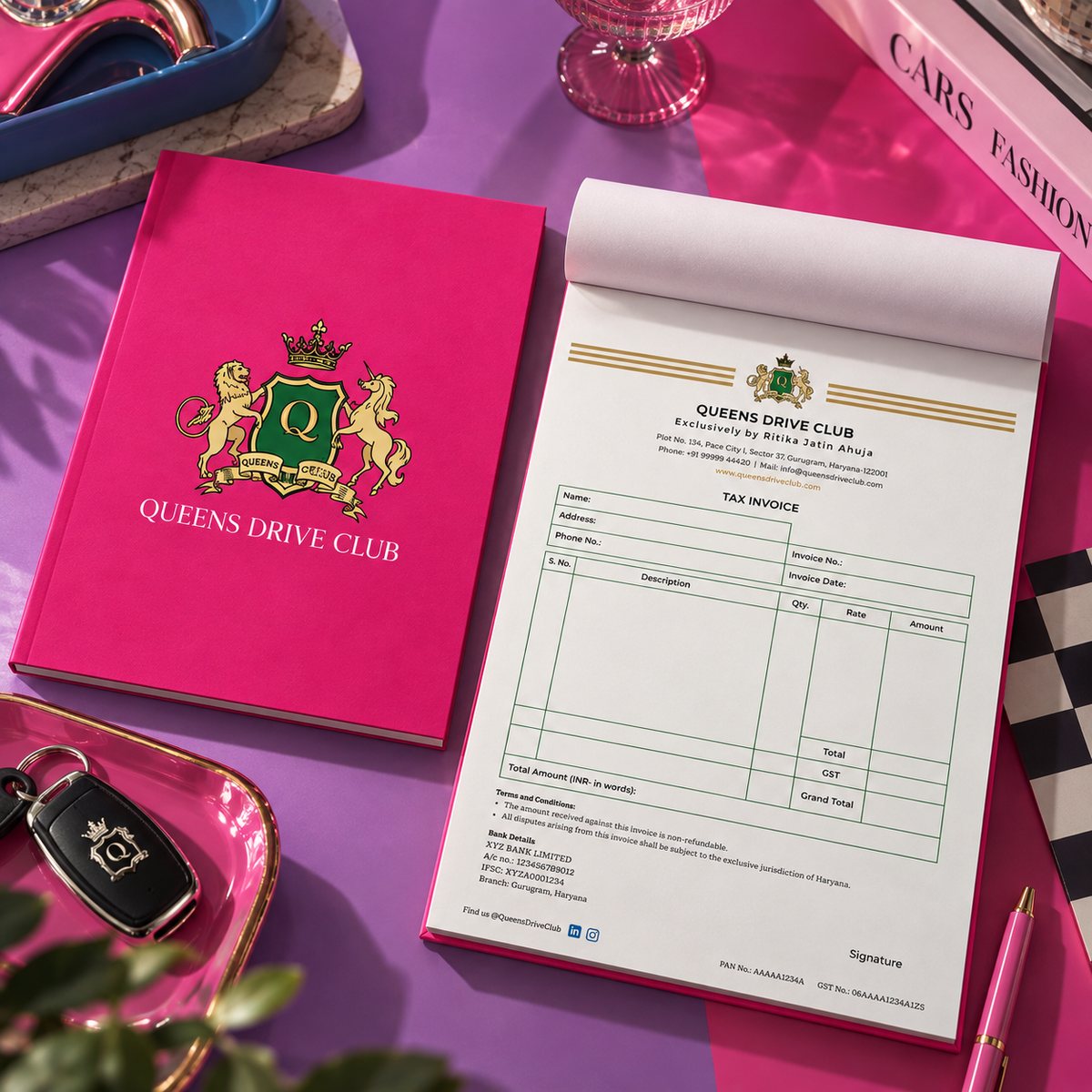 The same Queens Drive Club invoice book styled against a magenta and lilac surface with car keys and fashion books
